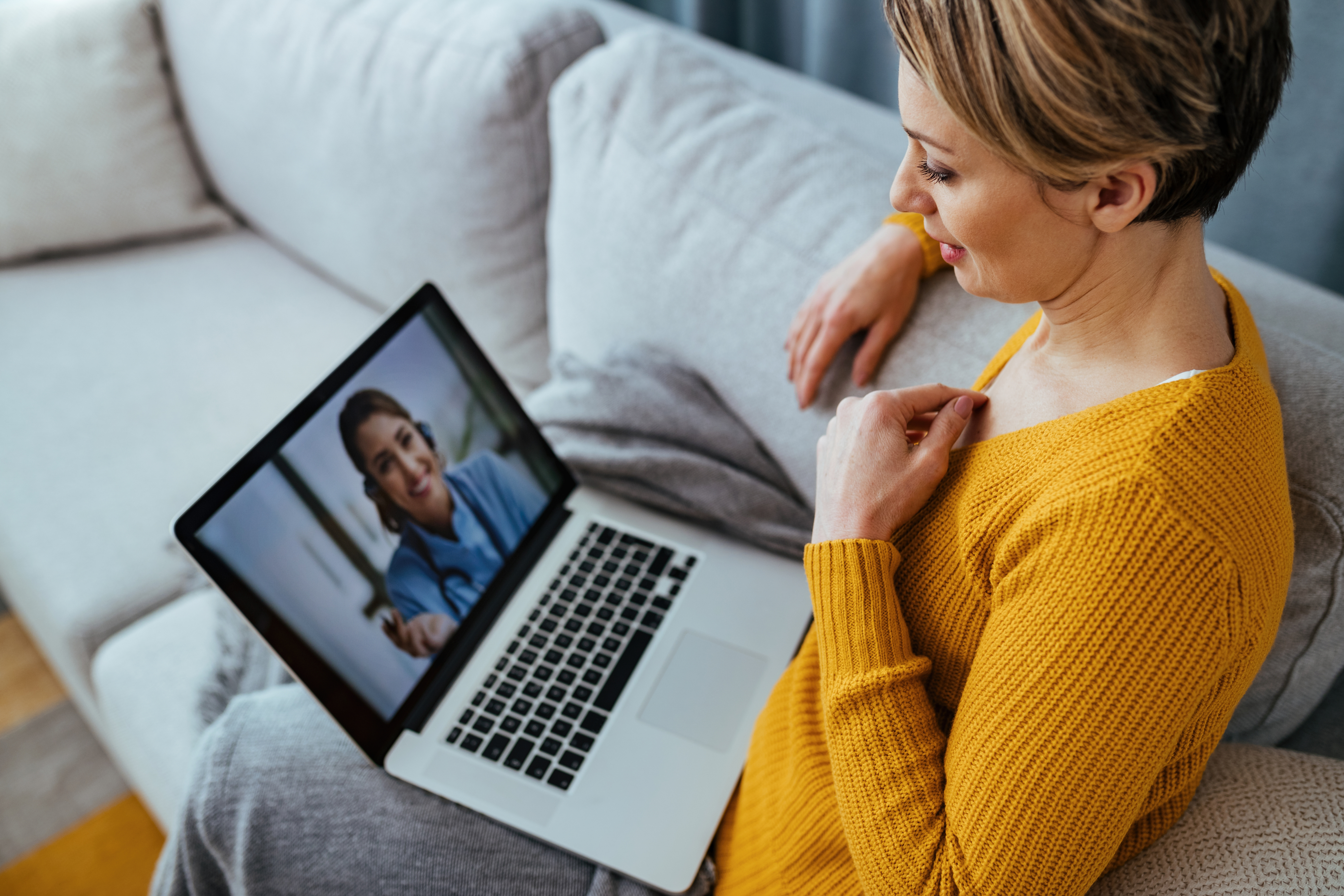 Paciente em consulta por vídeo com uma médica, usando o notebook em casa